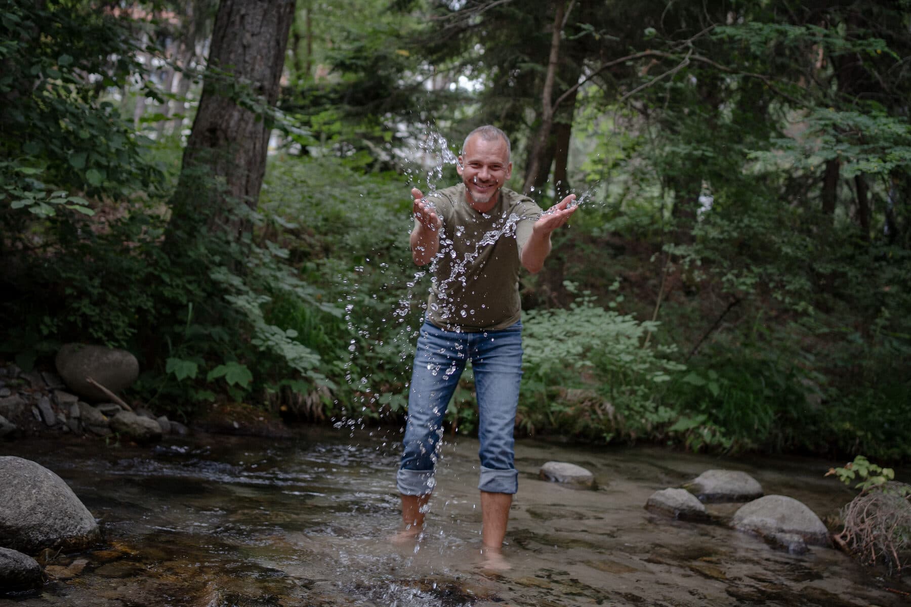 Sebastian Kühn spielt mit Wasser in einem Bach